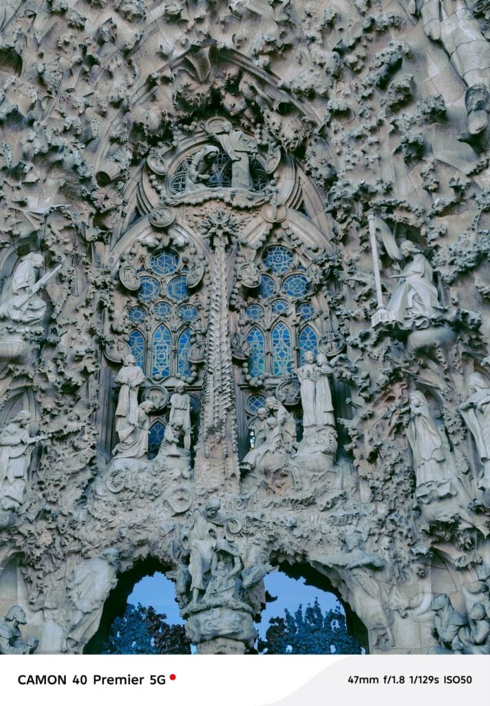 Tecno Camon 40 Pro 5G DXOMARK Global Ranking #1 Under $600 4 A close-up photograph showcasing the exquisite detail of a section of the Sagrada Familia's facade in Barcelona. The image highlights the numerous sculpted figures and the stained-glass window within the elaborate stonework. Photographed with a Tecno Camon 40 Premier 5G.