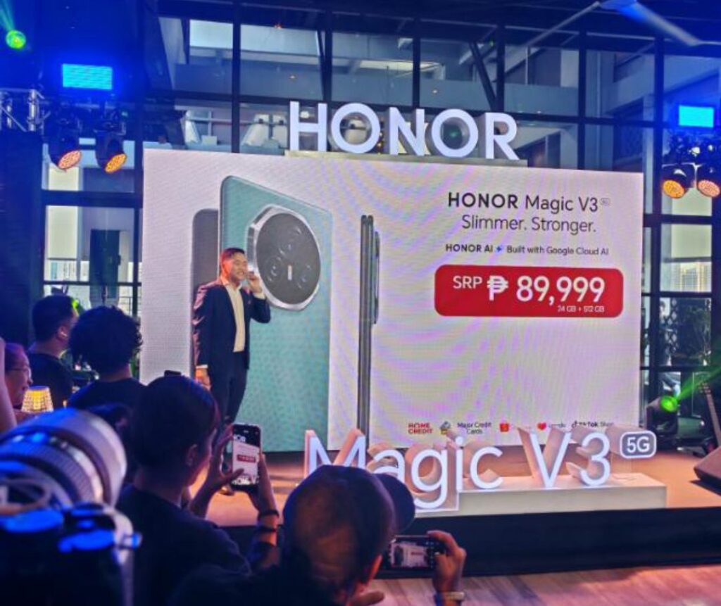 A launch event for the Honor Magic V3 5G smartphone in the Philippines. A large screen displays the phone, the brand name, and the price of ₱89,999. A presenter stands before the screen.