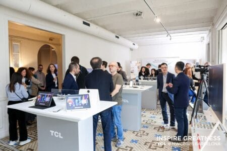 A display showcasing the TCL NXT 11 Plus tablet at the Mobile World Congress (MWC) 2025 in Barcelona. People are gathered around the booth, examining the tablet and other TCL products.