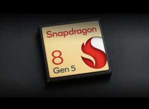 A close-up of the Snapdragon 8 Gen 5 chip logo, featuring a gold background with red and white accents, on a black surface.