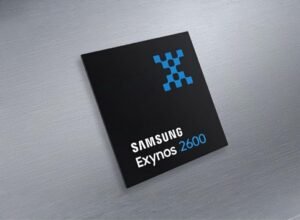 Close-up of a black Samsung Exynos 2600 chip with a blue pattern in the top right corner, lying on a brushed metal surface.
