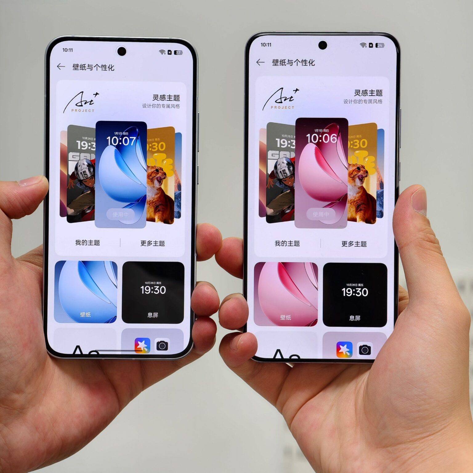 Two smartphones, likely from the same series, are shown side-by-side in a person's hands. Both phones display a customizable screen showing different wallpaper options and widgets. The screens show different color schemes: one is predominantly blue and the other pink. The text on the screen appears to be in Chinese.