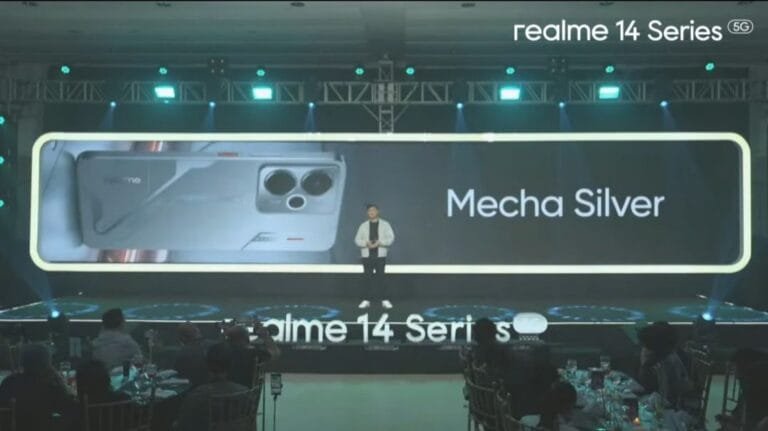 A close-up shot of the Realme 14T 5G smartphone in Mecha Silver. The phone is displayed prominently on a large screen at a product launch event.