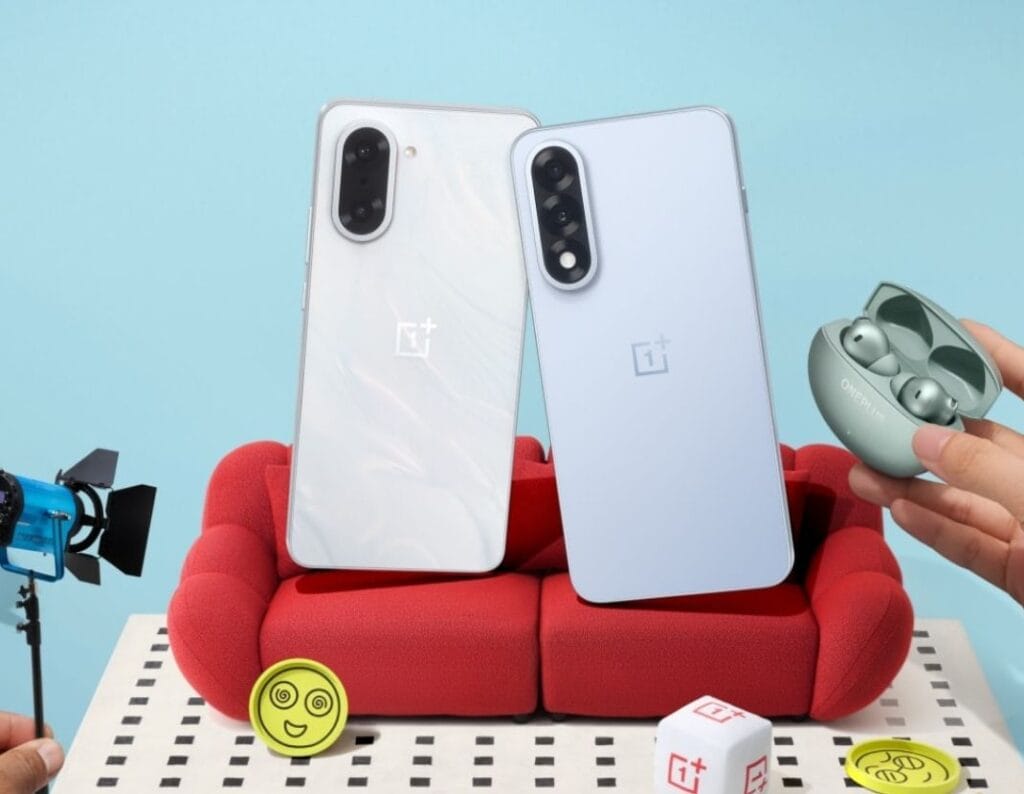 OnePlus Nord 5 | Flat OLED Display, 144Hz, and Snapdragon 8s Gen 3 1 Two OnePlus Nord 5 smartphones, one white and one light blue, are shown leaning against each other on a small red couch. A pair of OnePlus earbuds in a case rests nearby. The scene is playfully styled with miniature props.
