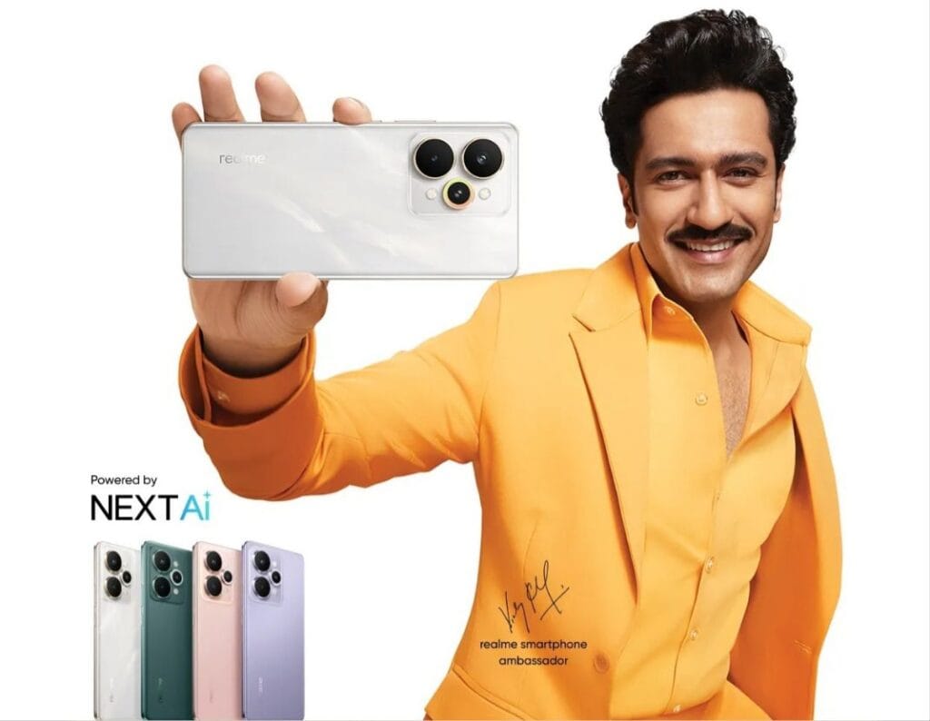 Realme 15 Series to Launch in India with Snapdragon 7 Gen 4 1 A promotional image for the Realme 15 Series smartphones. A man in a bright yellow blazer holds up a silver Realme 15 phone. Below, three additional Realme 15 phones in different colors (silver, green, and purple) are displayed. The image includes the tagline "Powered by NEXTAi" and the signature of a Realme smartphone ambassador.