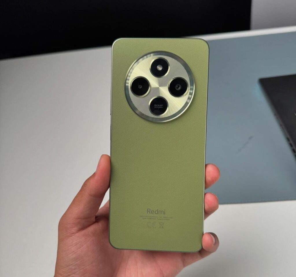 a person holding a smartphone xiaomi redmi 14r 5g with circular camera module in green color variant