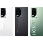 Close-up image displaying three Honor GT smartphones from the back. Each phone is a different color: white, black, and a gradient green. The "HONOR" branding is subtly embossed on the green and black models, while it is printed vertically on the white model. The camera module is visible on each phone, featuring three lenses.