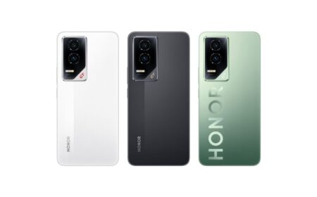 Close-up image displaying three Honor GT smartphones from the back. Each phone is a different color: white, black, and a gradient green. The "HONOR" branding is subtly embossed on the green and black models, while it is printed vertically on the white model. The camera module is visible on each phone, featuring three lenses.