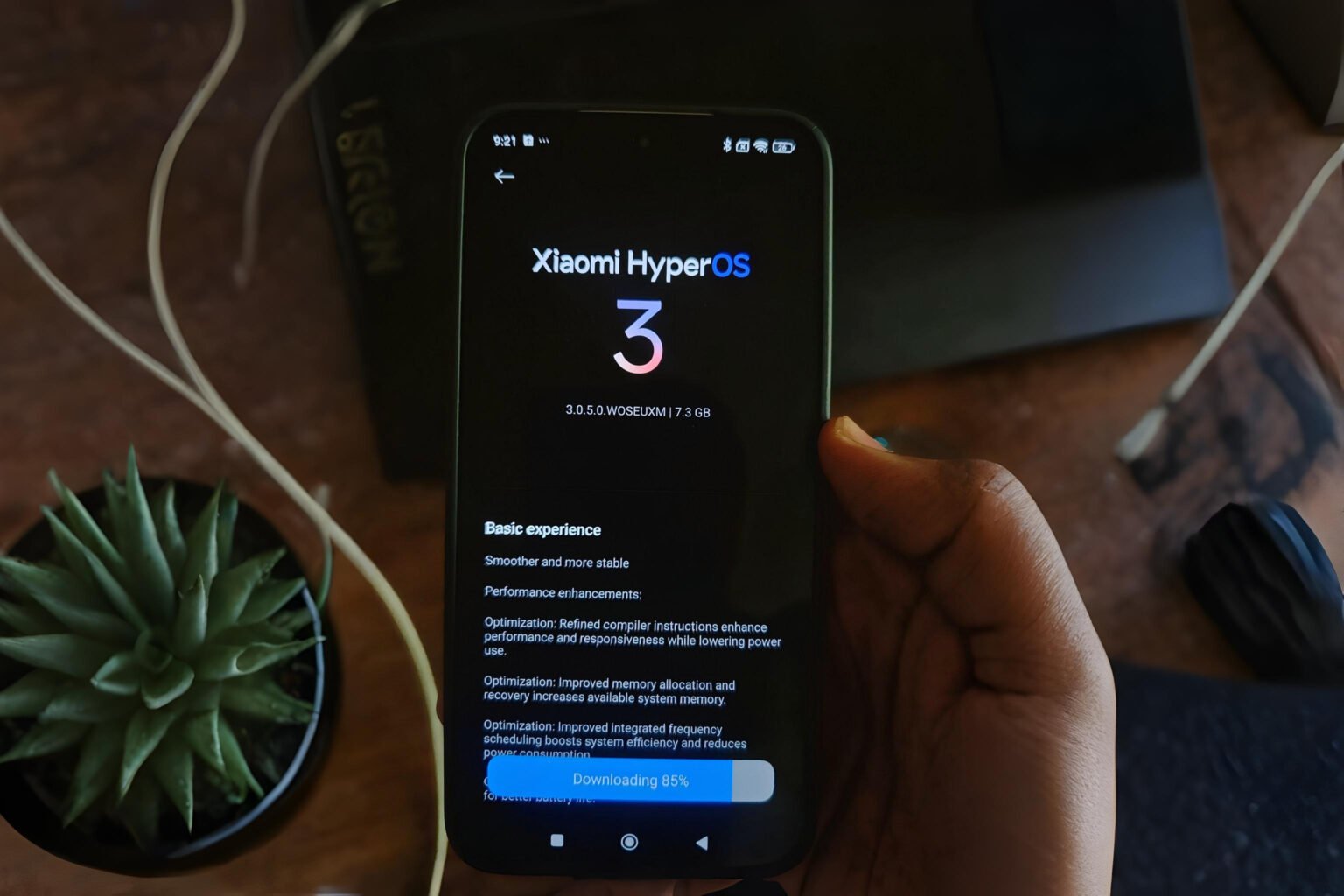 A smartphone displays the Xiaomi HyperOS 3 update screen, showing the logo, version number, and download progress.