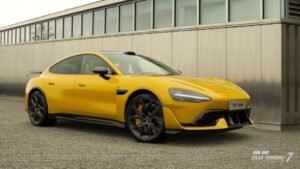 Yellow Xiaomi SU7 Ultra ’25 shown in Gran Turismo 7, parked outside a modern building.