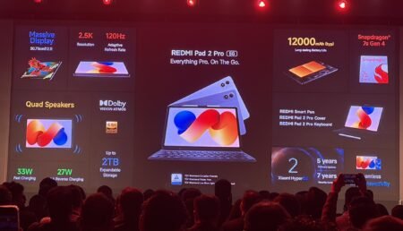 Photo from REDMI Pad 2 Pro 5G launch event – large screen shows the tablet with tagline "Everything Pro. On The Go." Key specs: 30.73cm (12.1") 2.5K 120Hz display, Snapdragon 7s Gen 4, 12000mAh battery, quad speakers with Dolby Vision-Atmos, 33W fast/27W reverse charging, up to 2TB expandable storage. Accessories include smart pen, cover, keyboard. Software: Xiaomi HyperOS with 5 years software/7 years security updates. TÜV certified. Audience visible in foreground.