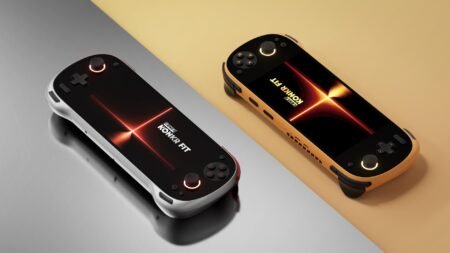 Two KONKR FIT handheld gaming consoles, one in Luminous Silver and one in Dragonveil Gold, resting on a split-tone reflective surface.