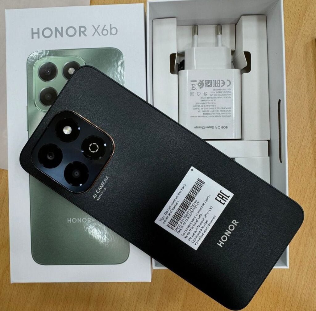 a smartphone in color black with box of honor x6b along-side of the charger.