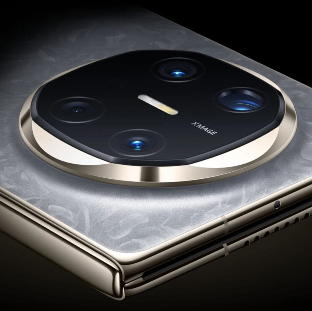 Huawei Mate X6 Price in the Philippines, Specs, and Features 3 High-resolution close-up of the Huawei Mate X6's rear camera system. The image shows a circular camera housing with three visible lenses, a flash, and the "XMAGE" branding. The phone's back is a light gray with a subtle textured finish, and the camera housing is accented with a gold-colored ring. A portion of the phone's side and speaker grille are also visible.