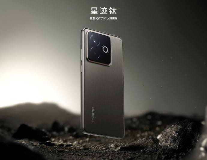 A promotional image showcases the Realme GT 7 Pro Racing Edition smartphone in its "Star Trail Titanium" color variant. The phone, subtly levitating above a dark, rocky surface, displays a brushed metal back with the Realme logo. The camera module is prominently featured, and the Chinese text above indicates the phone's name and model. The overall aesthetic is sleek, dark, and technologically advanced.