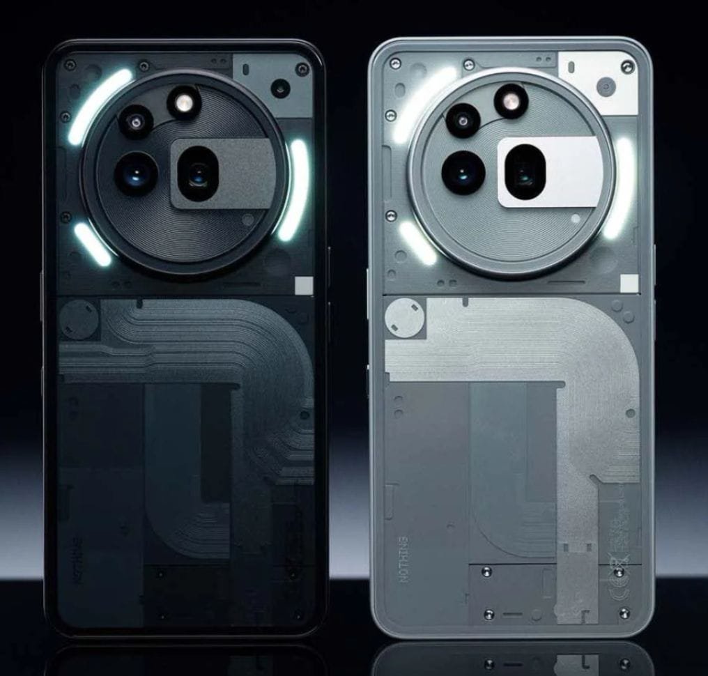 Close-up view of two Nothing Phone 3a Pro phones. The rear of each phone showcases a partially transparent design revealing internal components, and features the distinctive circular Glyph interface with illuminated lighting around the camera array.