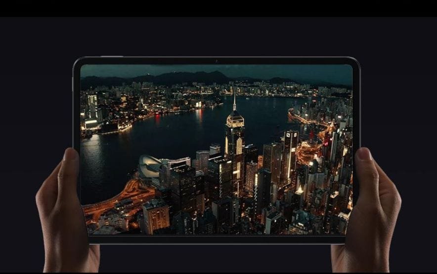Xiaomi Pad 7 Max Tipped to Launch with 14-Inch OLED Display and 120W Charging Close-up of hands holding a large Xiaomi Pad 7 Max tablet. The screen shows a vibrant aerial view of a city at night, highlighting the tablet's display quality.