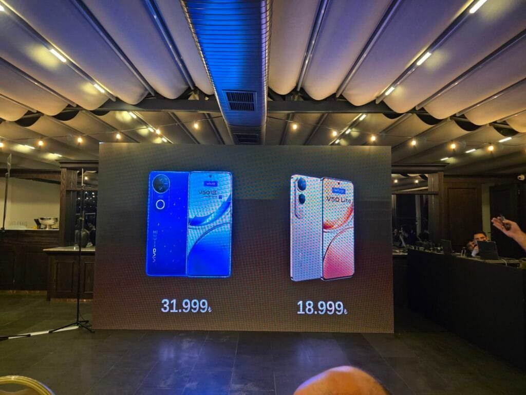 Vivo V50 Lite 5G Coming Soon to PH: Massive 6500mAh Bluevolt Battery w/ 90W Fast Charge 1 A large screen at a product launch event displays the Vivo V50 and Vivo V50 Lite smartphones. The Vivo V50 is shown in blue, and the Vivo V50 Lite 4G in a rose gold color. Prices are displayed beneath each phone in Turkish Lira (₺31,999 and ₺18,999 respectively).