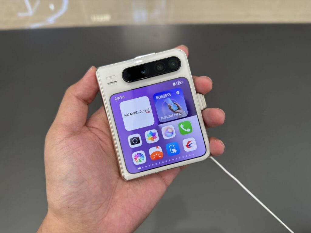 Huawei Pura X Clamshell Foldable Smartphone Launched in China 3 Close-up of a person's hand holding a Huawei Pura X foldable phone, showing the home screen with apps and widgets.
