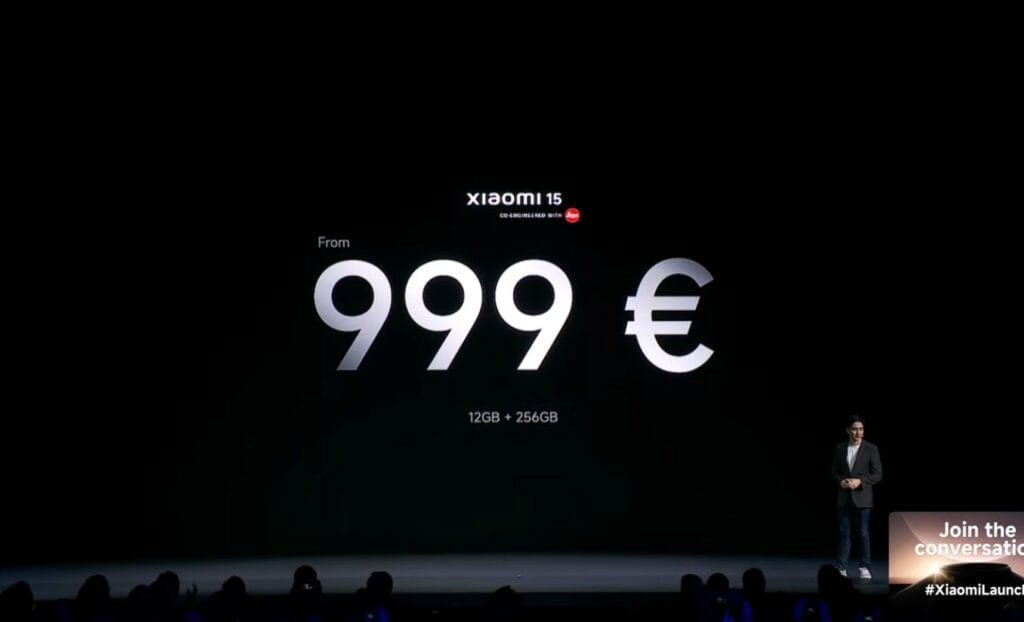 Xiaomi 15 5G Launched Globally Featuring a Triple 50MP Leica Camera & SD 8 Elite 2 A large screen at a Xiaomi product launch event displays the price of the Xiaomi 15 5G: €999. The text also specifies that this price is for the 12GB + 256GB configuration. A presenter stands on stage to the right.