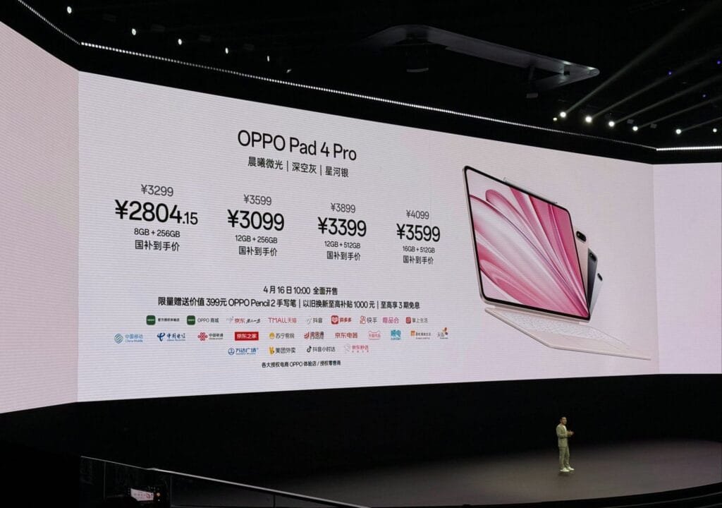 A large screen displays promotional material for the Oppo Pad 4 Pro tablet, showcasing the device in a sleek design. The screen also shows pricing in Chinese Yuan (CNY) for various storage configurations, along with logos of various online retailers where the tablet can be purchased. A person stands on a stage below the screen.