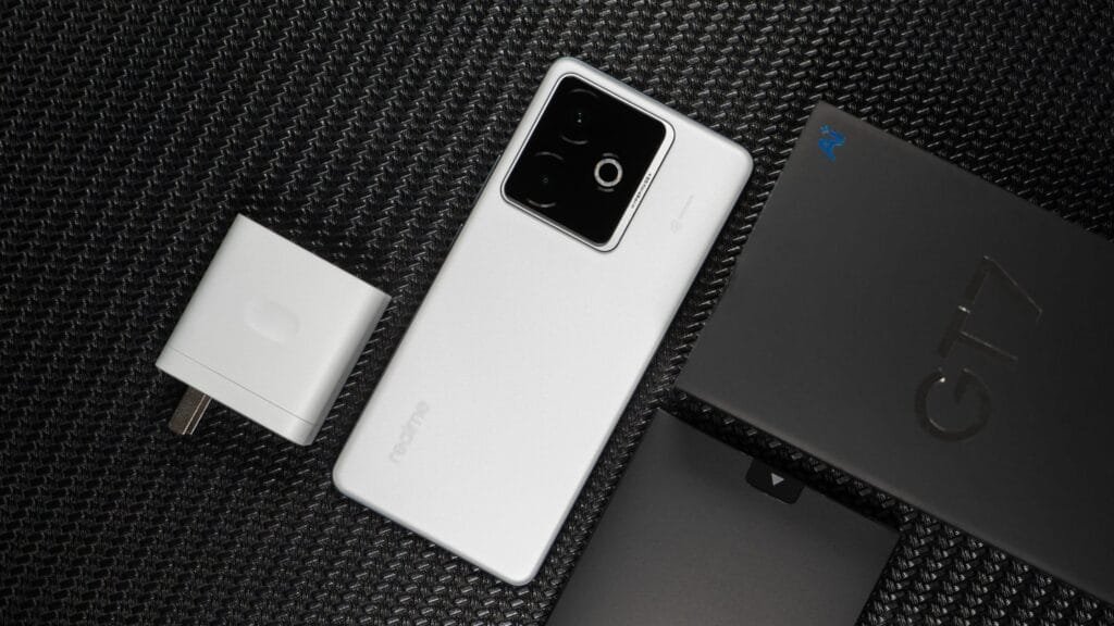 Realme GT 7 RMX5061 Global Variant Spotted with MediaTek Dimensity 9400e Chipset on Geekbench 1 A white Realme GT 7 smartphone lies on a black textured surface next to its charger and retail box.