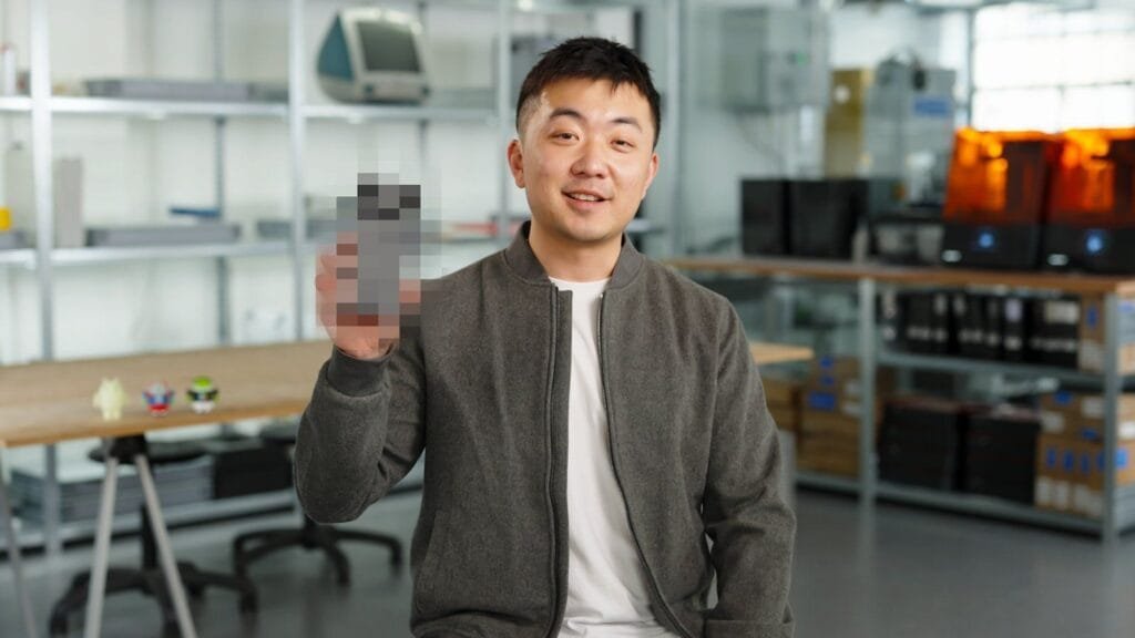 Carl Pei, CEO of Nothing, smiles and holds up a partially pixelated image of the Nothing Phone 3.