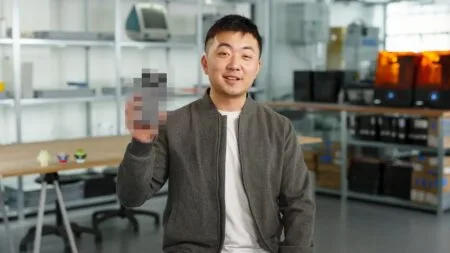 Carl Pei, CEO of Nothing, smiles and holds up a partially pixelated image of the Nothing Phone 3.