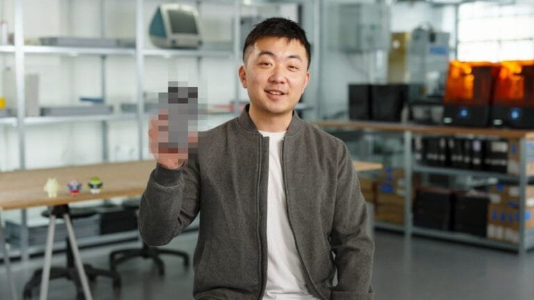 Carl Pei, CEO of Nothing, smiles and holds up a partially pixelated image of the Nothing Phone 3.