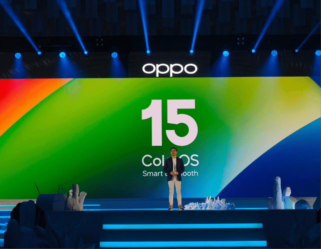 A person standing on stage at a product launch event for OPPO's ColorOS 15 operating system. The large screen behind them displays the ColorOS 15 logo.