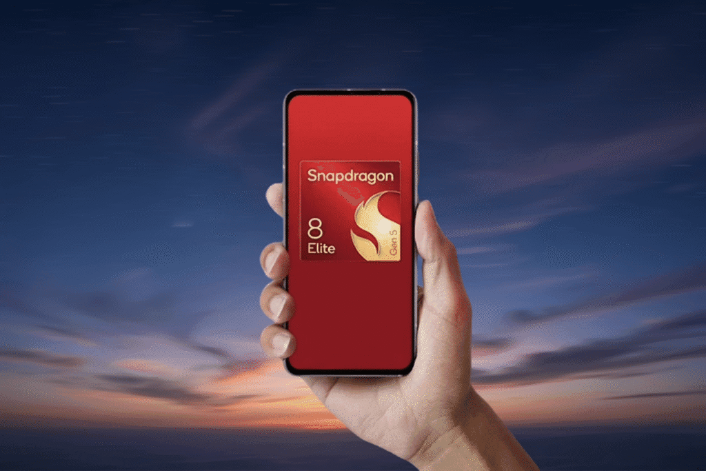 A hand holds a smartphone with a red screen showcasing the Snapdragon 8 Elite Gen 5 logo. The background features a vibrant sunset sky.