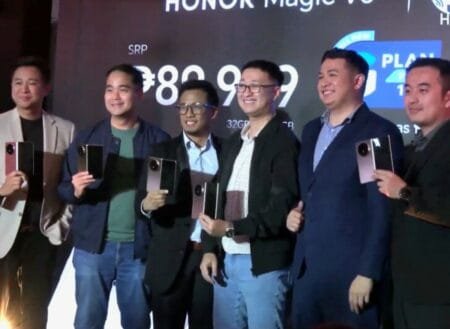 Six men in business attire pose with the Honor Magic V5 at its Philippine launch event. The backdrop displays the phone's SRP and partnership with Globe Telecom.