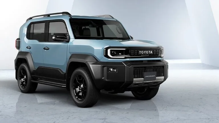 Toyota Unveils Next-Generation Land Cruiser FJ, Set for 2026 Launch A light blue Toyota Land Cruiser FJ with black trim, featuring a boxy design, is showcased against a bright studio backdrop.