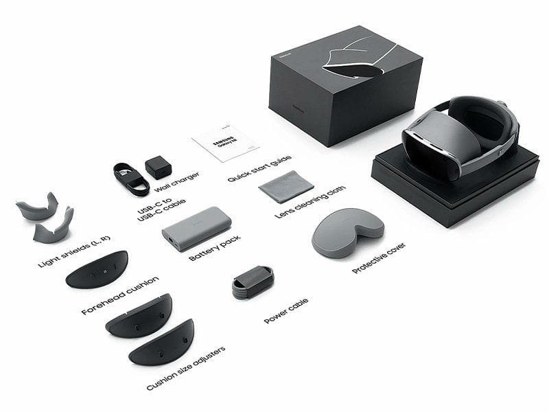 Samsung Galaxy XR Launched Globally 2 An unboxing shot of the Samsung Galaxy XR, displaying the headset on a stand next to its packaging. The layout includes accessories such as light shields, forehead cushions, cushion size adjusters, a USB-C to USB-C cable, a wall charger, a battery pack, a power cable, a quick start guide, a lens cleaning cloth, and a protective cover, all neatly arranged on a white surface.