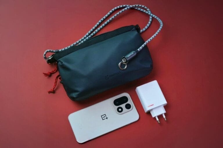 OnePlus 15 Launched in China with Starting Price of CNY 3,999 OnePlus 15 sand dune edition on a red surface, showcasing its design alongside a charger and a stylish OnePlus crossbody bag.