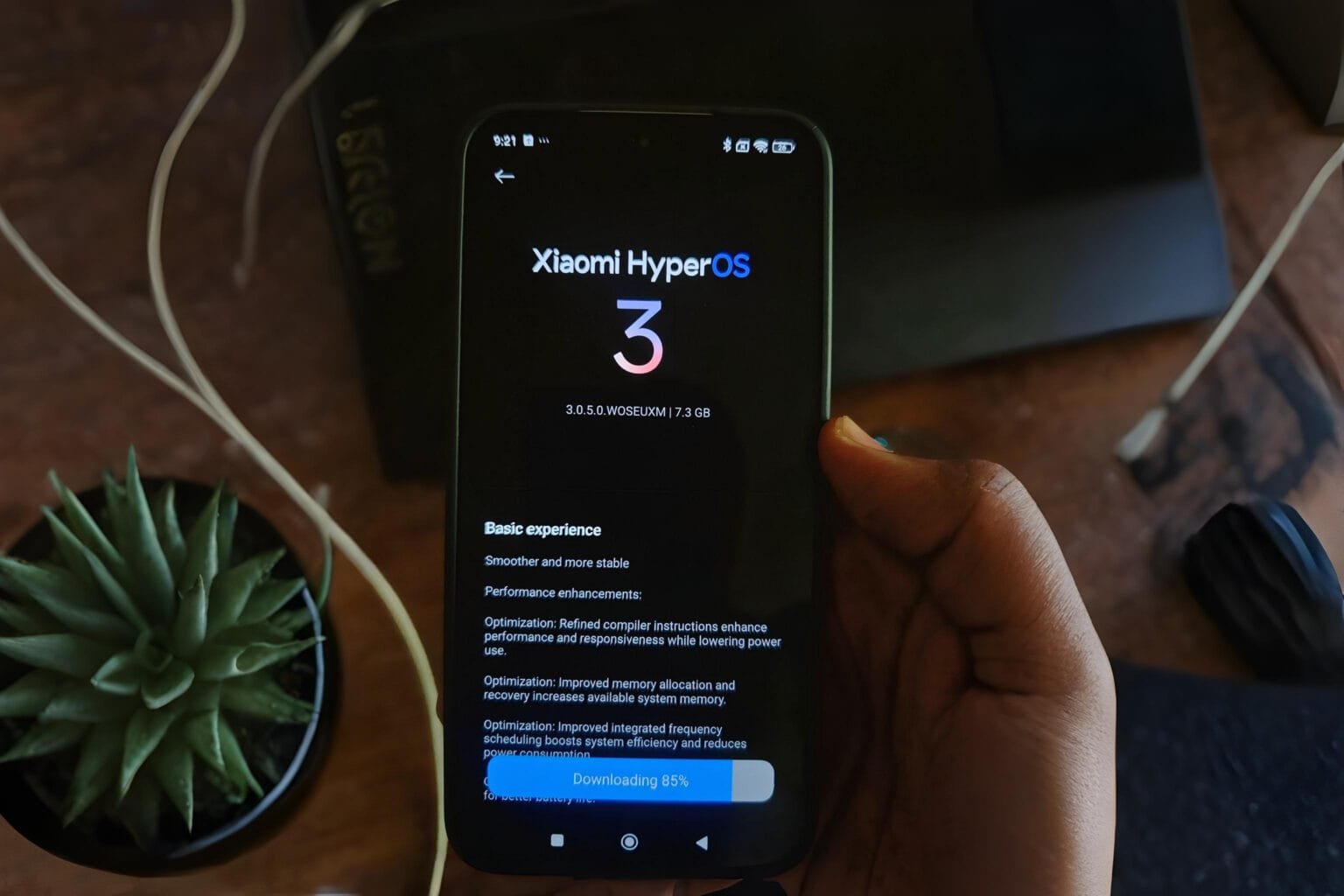 A smartphone displays the Xiaomi HyperOS 3 update screen, showing the logo, version number, and download progress.