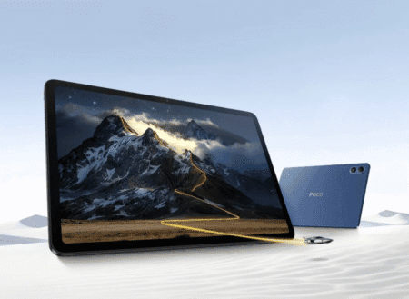 A blue Poco Pad M1 tablet is shown on a light sandy surface. The screen displays a scenic mountain range with a winding path. Another Poco Pad M1 is in the background.