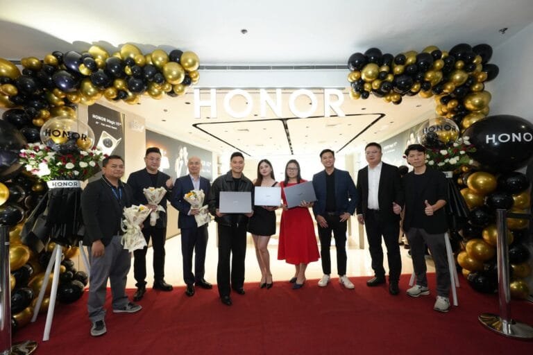 HONOR Opens 200th Store in the Philippines at SM City Manila! A group of people stand in front of an HONOR store, decorated with black and gold balloons, holding laptops and bouquets, celebrating the opening of HONOR Philippines' 200th store.