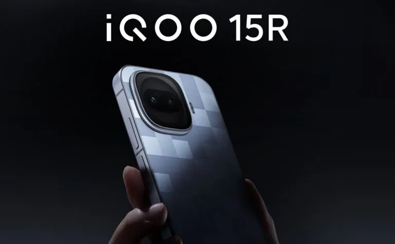 Promotional image of the iQOO 15R smartphone. The device is held in a hand, showcasing its back with a textured checkered pattern and a large, rounded camera module with dual lenses. The model name 'iQOO 15R' is displayed in bold white text at the top against a dark background.