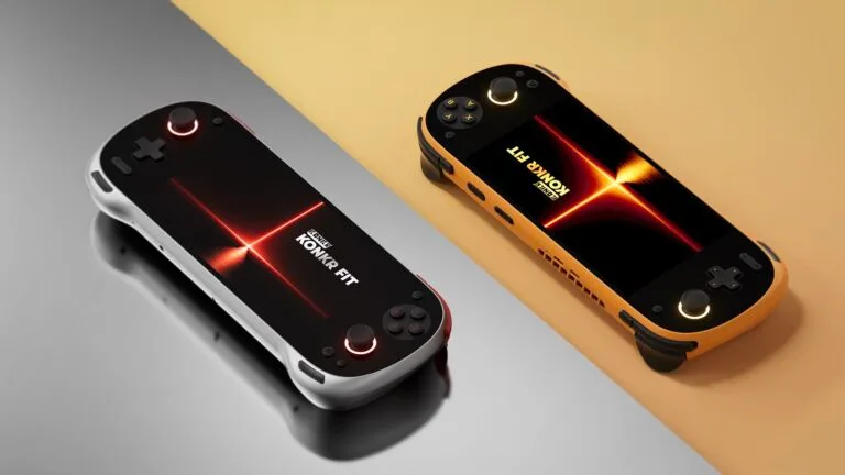 AYANEO KONKR FIT New Release Starts at $999 Two KONKR FIT handheld gaming consoles, one in Luminous Silver and one in Dragonveil Gold, resting on a split-tone reflective surface.