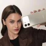 Infinix Note 60, Note 60 Pro, and Note 60 Ultra Appear on Geekbench Ahead of Global Launch 4 A woman holding the Infinix Note 60 Pro smartphone, showcasing its gold back design with a rectangular camera module and dual rear cameras.