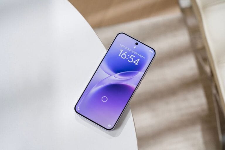 Vivo X300 FE (V2537) Appears in Several Certifications for Global Launch A modern smartphone, likely a Vivo S50 Pro mini, with a vibrant purple and blue-gradient display showing the date 12月17日 (December 17th) and time 16:54. The phone has a subtle punch-hole camera at the top center and thin bezels, resting diagonally on a white, minimalist surface.