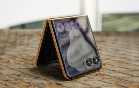 Motorola Razr 70 foldable smartphone partially folded in tent mode, showing its external OLED display with dual rear cameras on the cover panel.