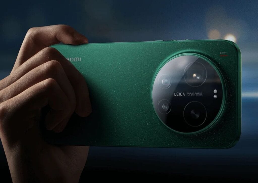 Xiaomi 17 Ultra Price in the Philippines is ₱99,999 for the 16GB/512GB Variant 2 A close-up, horizontal view of the back of a dark green Xiaomi 17 Ultra. A hand is shown holding the device, emphasizing the large, circular glass camera island that features the Leica logo and multiple lenses. The phone has a textured, shimmering finish, and the word "Ultra" is subtly visible in red script near the top corner.