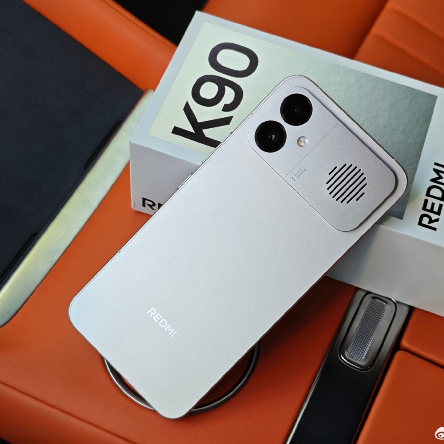 Back view of the Silver Redmi K90 Max gaming smartphone placed alongside its retail box