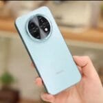 Light blue Huawei Enjoy 90 Plus smartphone held in hand, showcasing its circular camera module with four lenses and Huawei logo on the back panel
