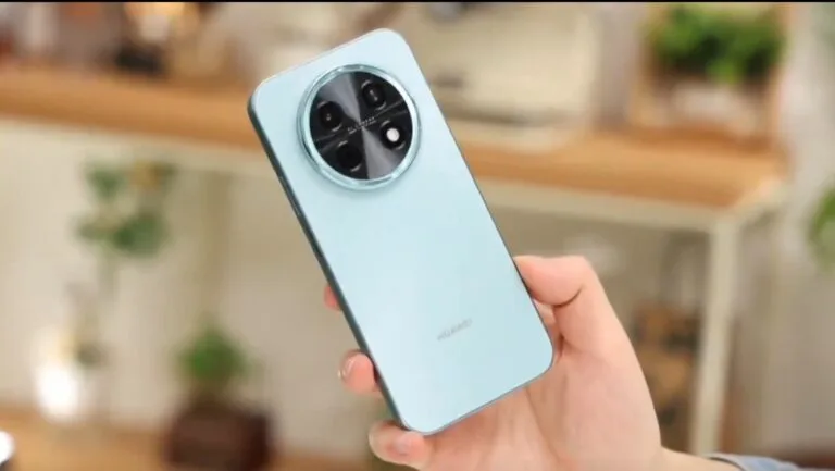 Light blue Huawei Enjoy 90 Plus smartphone held in hand, showcasing its circular camera module with four lenses and Huawei logo on the back panel