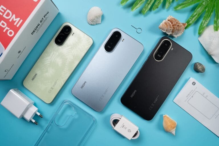 Flat-lay shot of three Redmi A7 Pro smartphones in light green, light blue, and black colorways, displayed alongside their retail box, 15W charger, USB cable, clear protective case, SIM tool, and user manual, arranged on a bright blue surface decorated with seashells and green leaves.