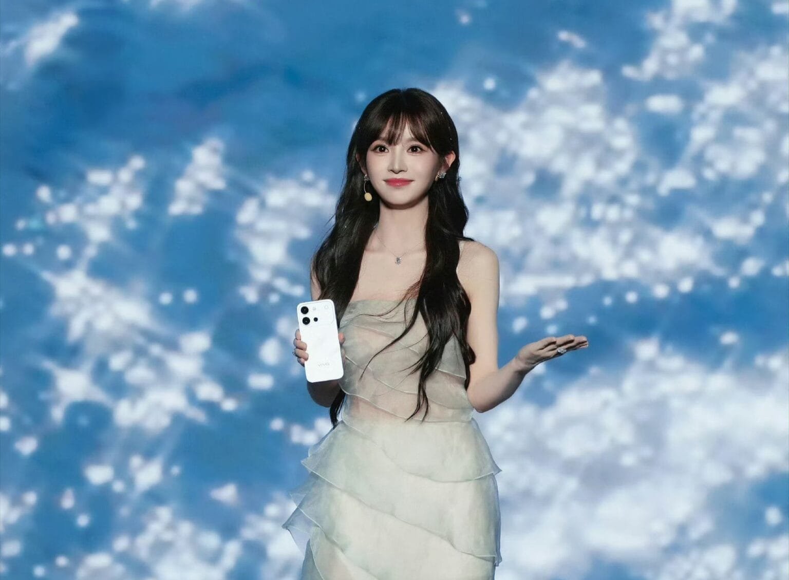 Chinese actress Tian Xiwei holding the white Vivo S60 Vitality Edition smartphone, posing elegantly at the launch event with a blue cloudy background
