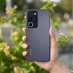 Realme P4R 5G Launched: 8,000mAh Battery and 50MP Samsung Camera 4 Back view of the Realme P4R 5G in matte dark finish, held in hand against soft green outdoor background; triple‑camera module visible at the top left, with vertical Realme branding near the bottom.
